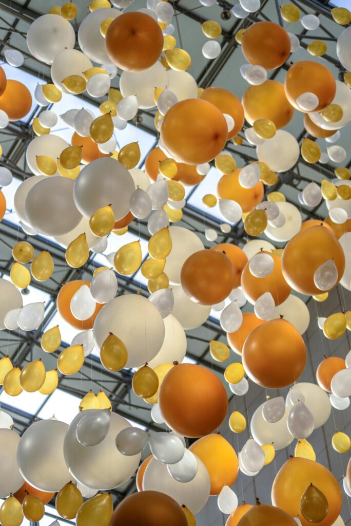 pexels-photo-226737-226737 Vibrant arrangement of orange, white, and yellow balloons hanging in an indoor celebration space.